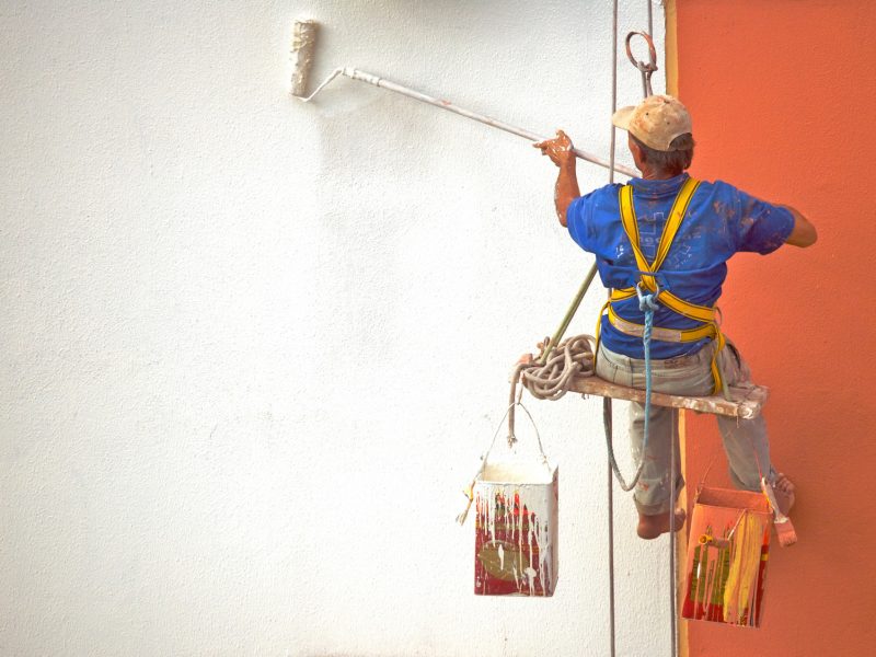 Hanging Painter painting wall with roller